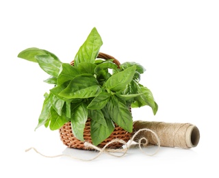 Photo of Green basil in basket and coil of rope on white background