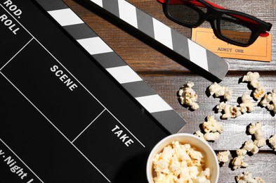 Photo of Flat lay composition with clapperboard and popcorn on wooden table