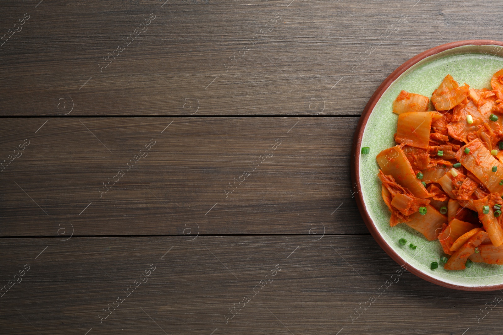 Photo of Plate of delicious kimchi with Chinese cabbage on wooden table, top view. Space for text