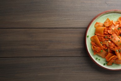 Photo of Plate of delicious kimchi with Chinese cabbage on wooden table, top view. Space for text