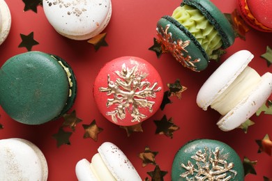 Photo of Beautifully decorated Christmas macarons and confetti on red background, flat lay