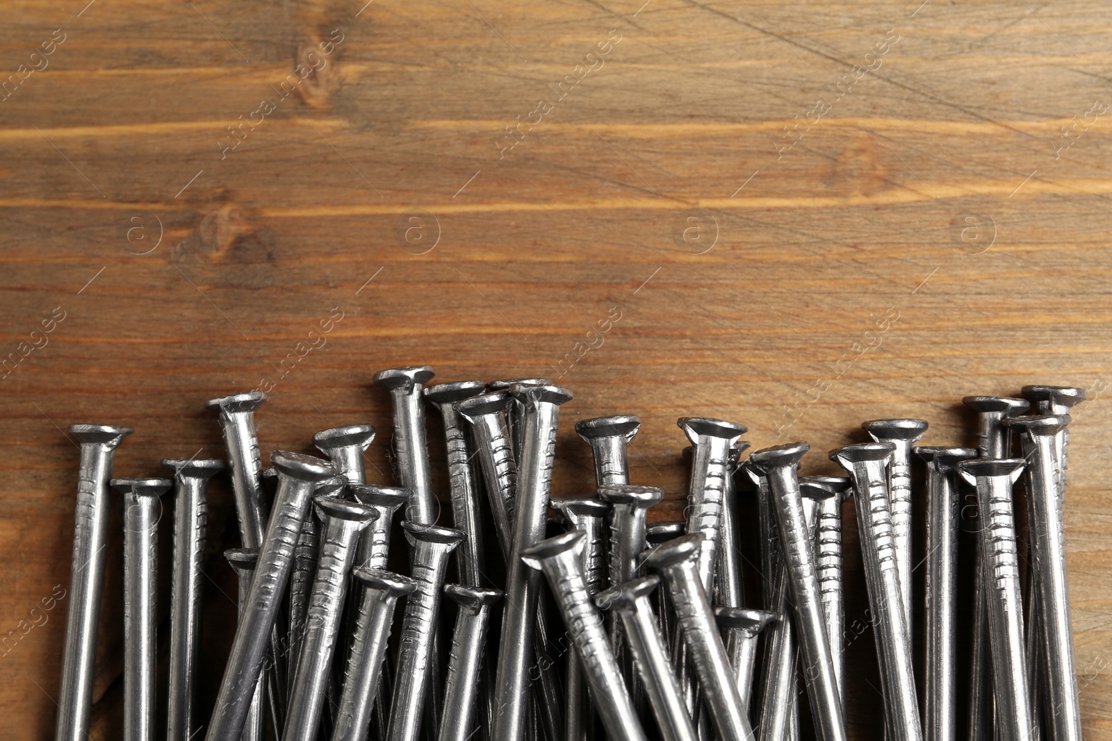 Photo of Pile of metal nails on wooden background, flat lay. Space for text