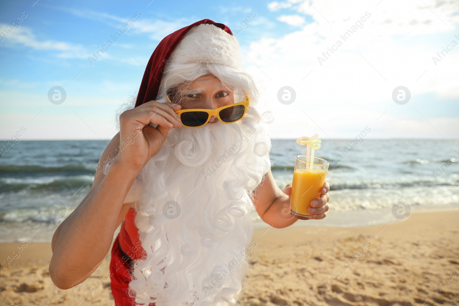 Photo of Santa Claus with cocktail on beach. Christmas vacation