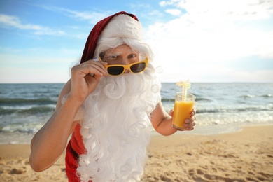 Photo of Santa Claus with cocktail on beach. Christmas vacation