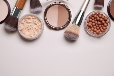 Photo of Different face powders and makeup brushes on light background, flat lay. Space for text