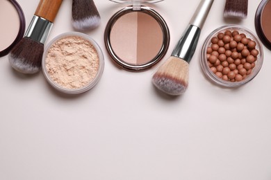 Different face powders and makeup brushes on light background, flat lay. Space for text