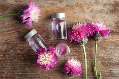 Photo of Flat lay composition with essential oils and flowers on wooden background