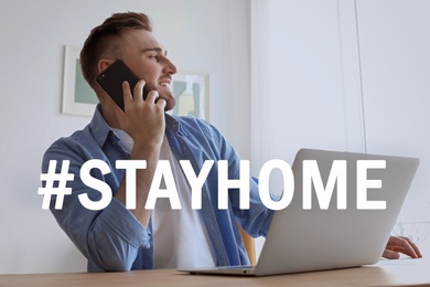 Image of Hashtag Stayhome - protective measure during coronavirus pandemic. Young man talking on phone while working with laptop indoors