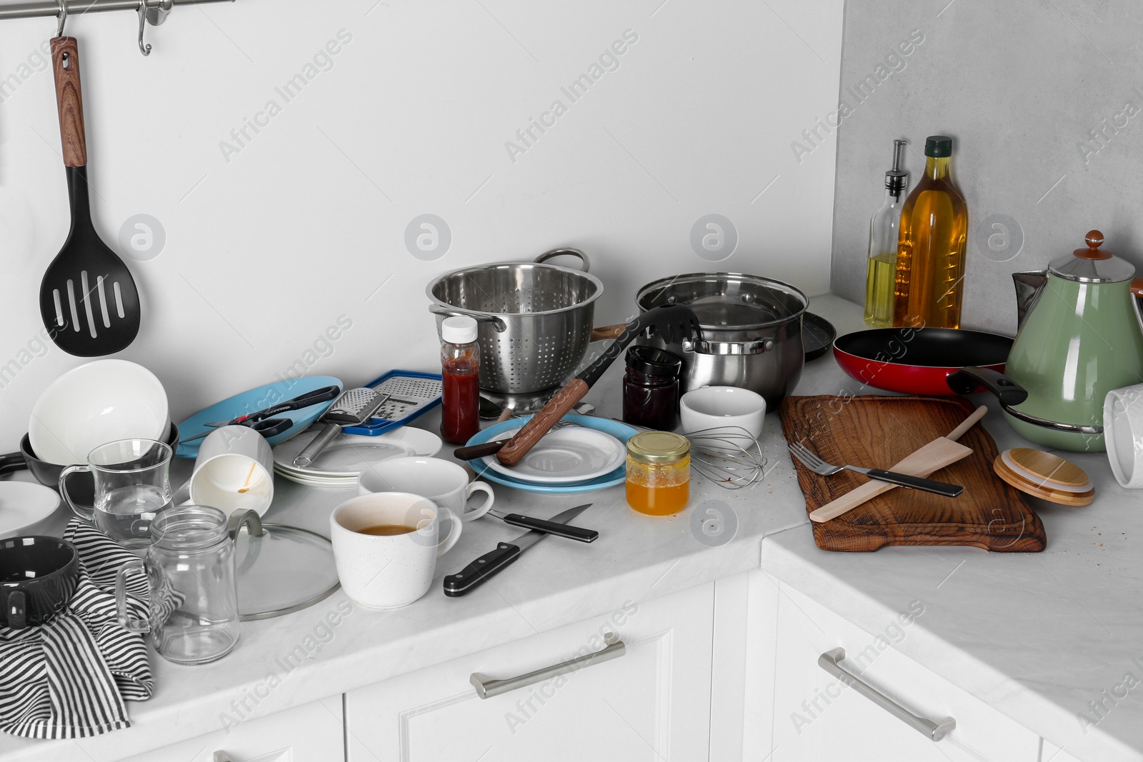 Photo of Many dirty utensils, cookware and dishware on countertop in messy kitchen