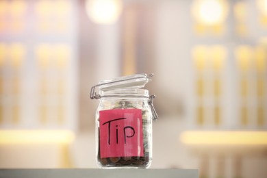 Photo of Tip jar with money on table against blurred background