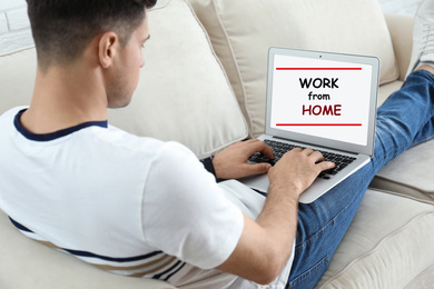 Image of Man using modern laptop on sofa indoors. Work from home