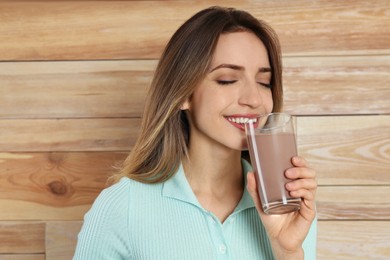 Photo of Young woman drinking chocolate milk on wooden background