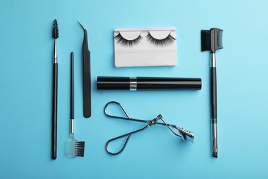 Flat lay composition of professional makeup tools and false eyelashes on color background