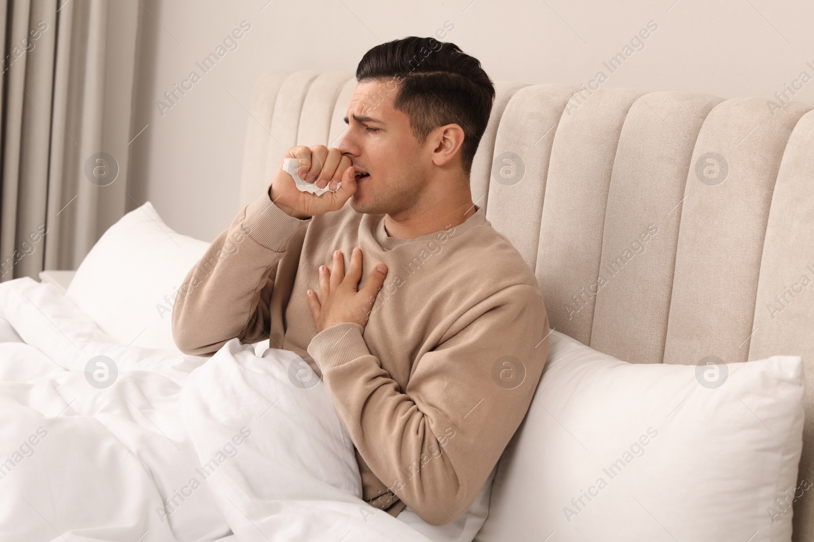 Photo of Sick man with tissue suffering from cold in bed at home