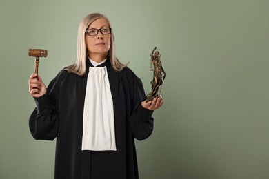 Photo of Senior judge with gavel and figure of Lady Justice on green background. Space for text
