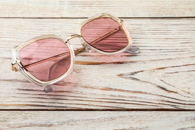 Photo of New stylish sunglasses on white wooden table, space for text