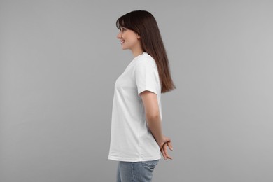 Smiling woman in white t-shirt on grey background