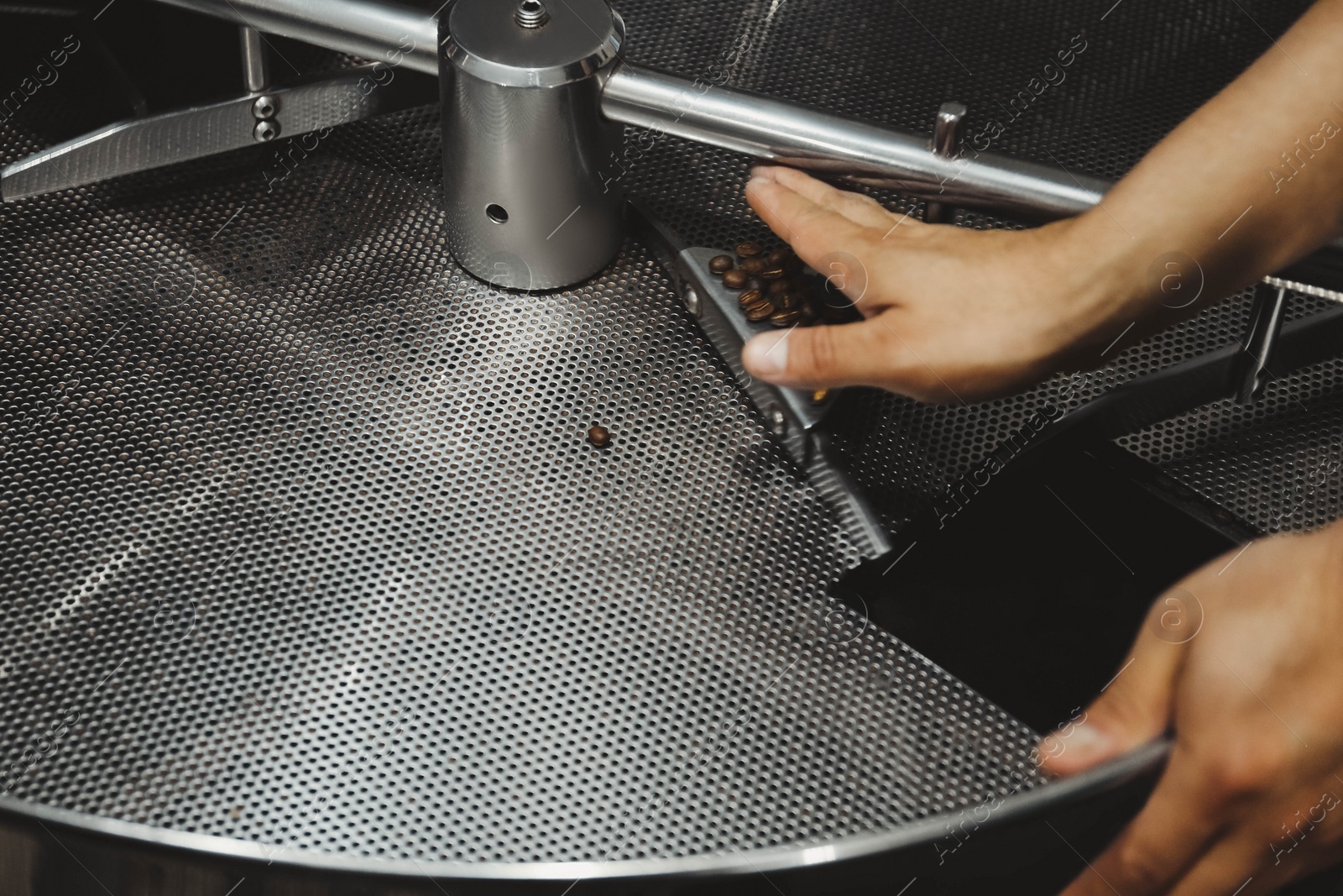 Photo of Man near coffee roaster machine indoors, closeup