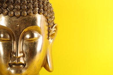 Photo of Beautiful golden Buddha sculpture on yellow background, closeup. Space for text