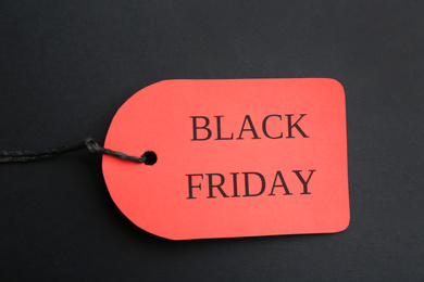 Red tag with words BLACK FRIDAY on dark background, top view