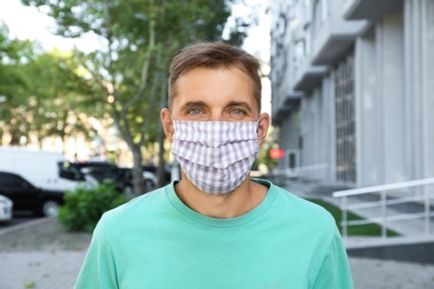 Photo of Man wearing handmade cloth mask outdoors. Personal protective equipment during COVID-19 pandemic
