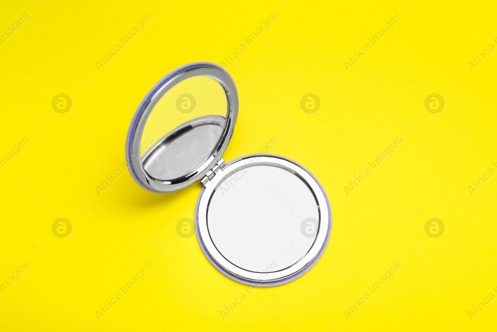 Photo of Stylish cosmetic pocket mirror on yellow background, top view