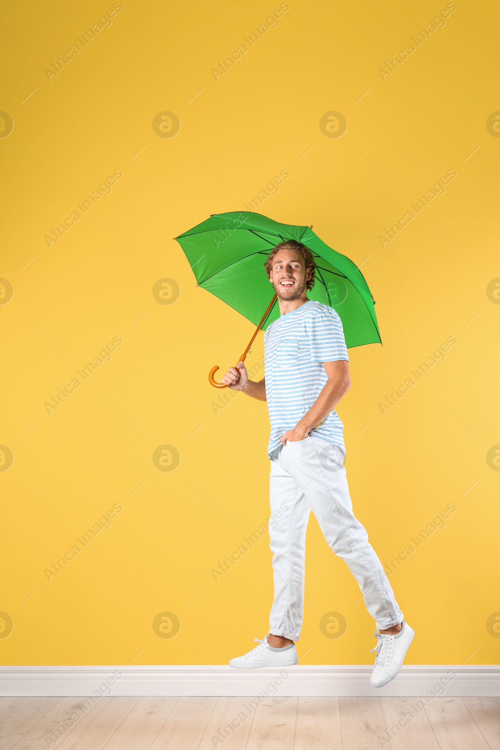 Photo of Man with green umbrella near color wall