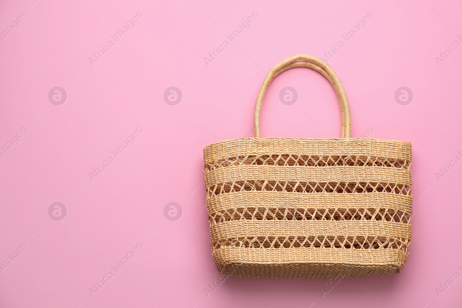 Photo of Elegant woman's straw bag on pink background, top view. Space for text