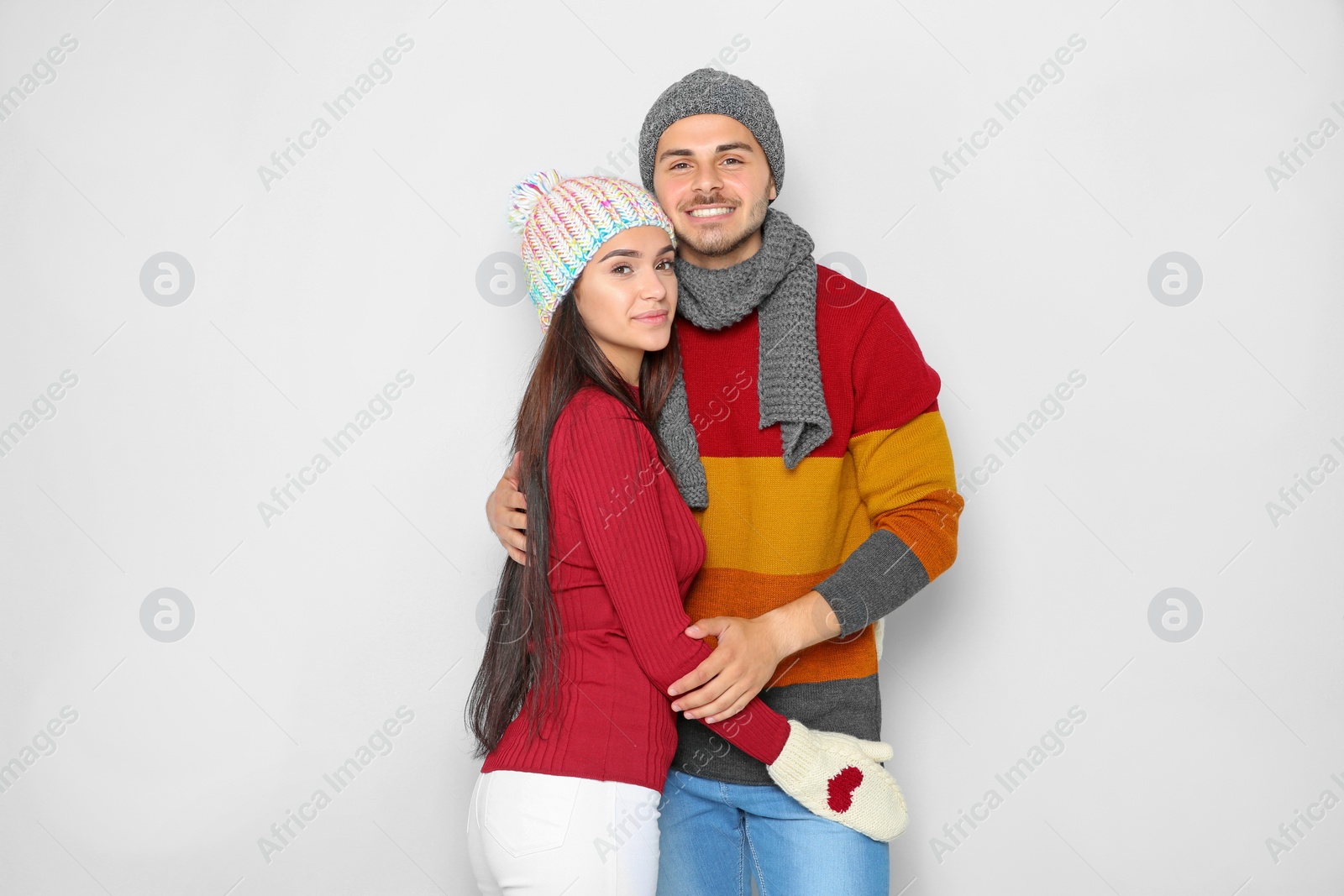 Photo of Young happy couple in warm clothes on light background. Christmas celebration