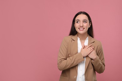 Photo of Thank you gesture. Beautiful grateful woman with hands on chest against pink background, space for text