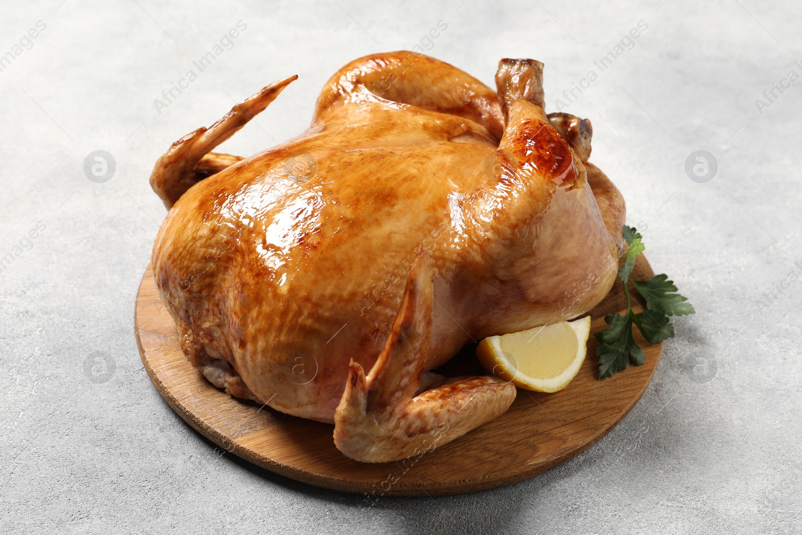 Photo of Tasty roasted chicken with parsley and lemon on light grey table