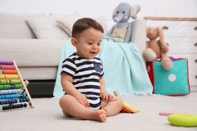 Photo of Cute baby boy playing with toys on floor at home