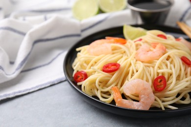 Photo of Tasty spaghetti with shrimps and chili pepper on grey table, closeup. Space for text