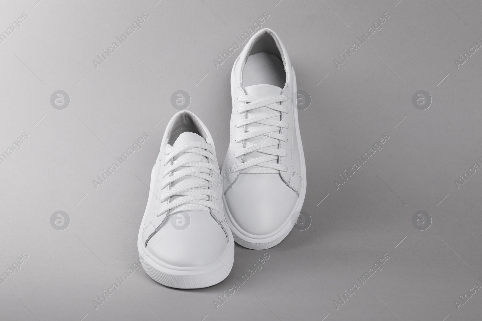 Photo of Pair of stylish white sneakers on grey background