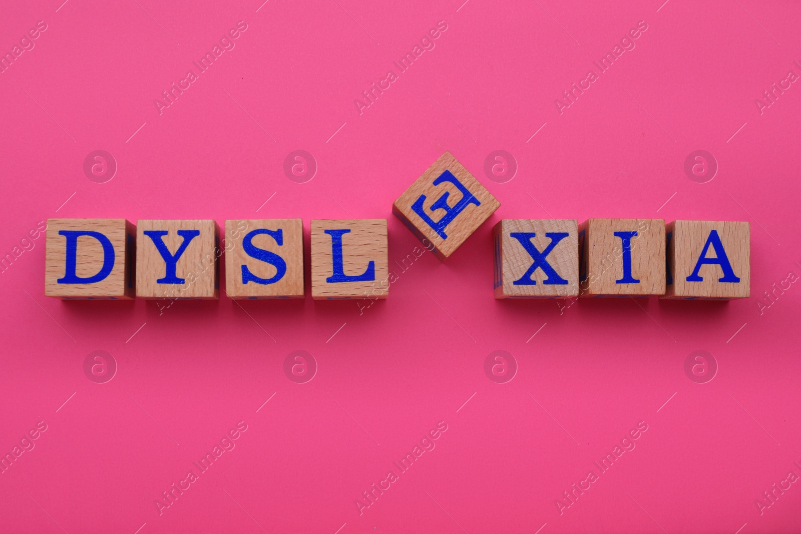 Photo of Wooden cubes with word Dyslexia on pink background, flat lay