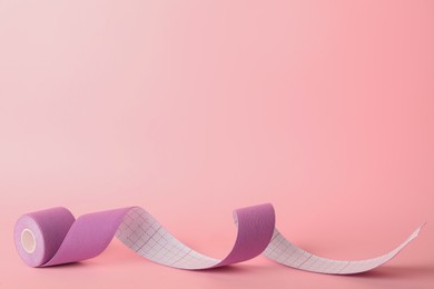 Bright kinesio tape in roll on pink background. Space for text