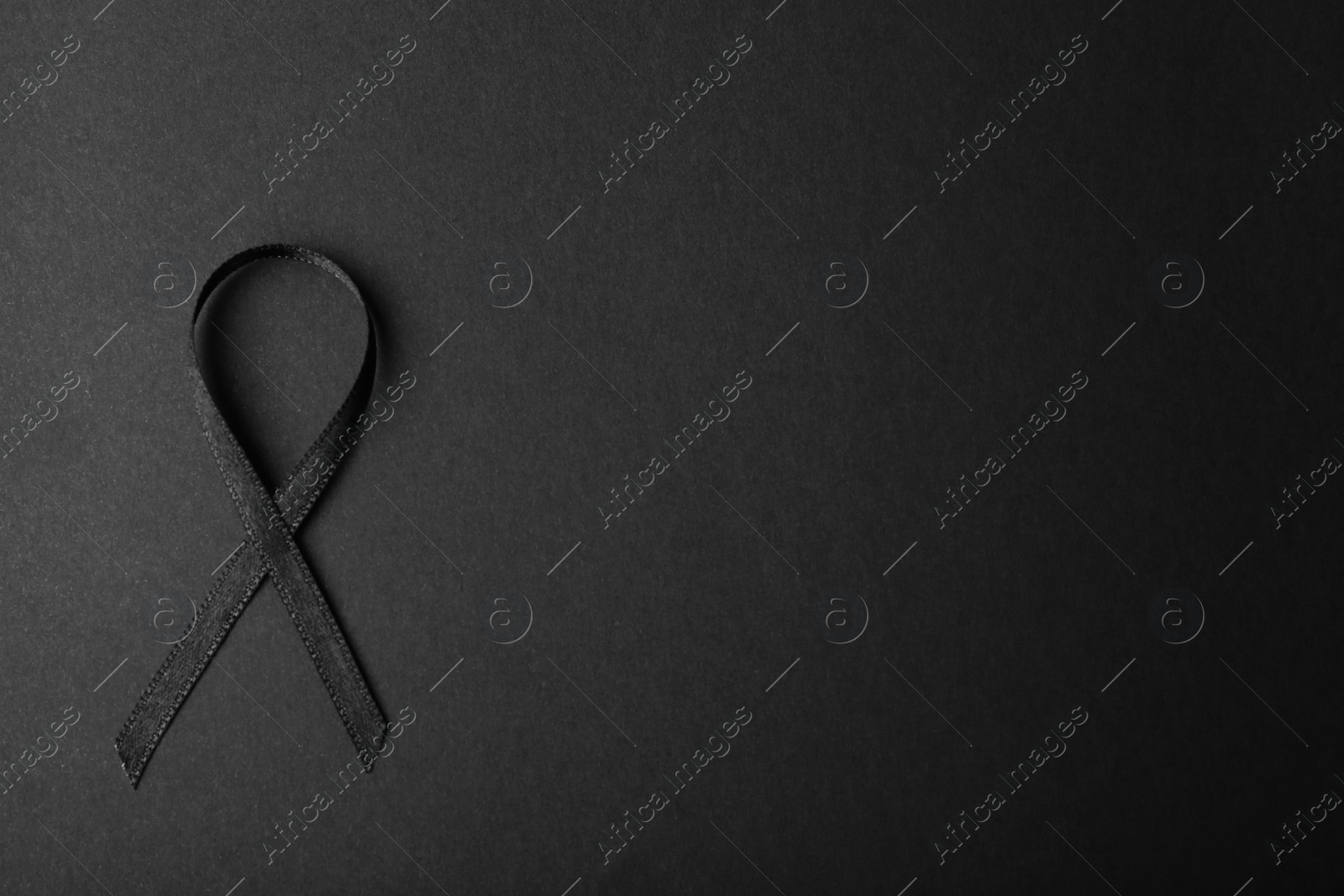 Photo of Black ribbon and space for text on dark background, top view. Funeral accessory