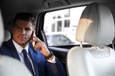 Handsome man talking on phone in modern car