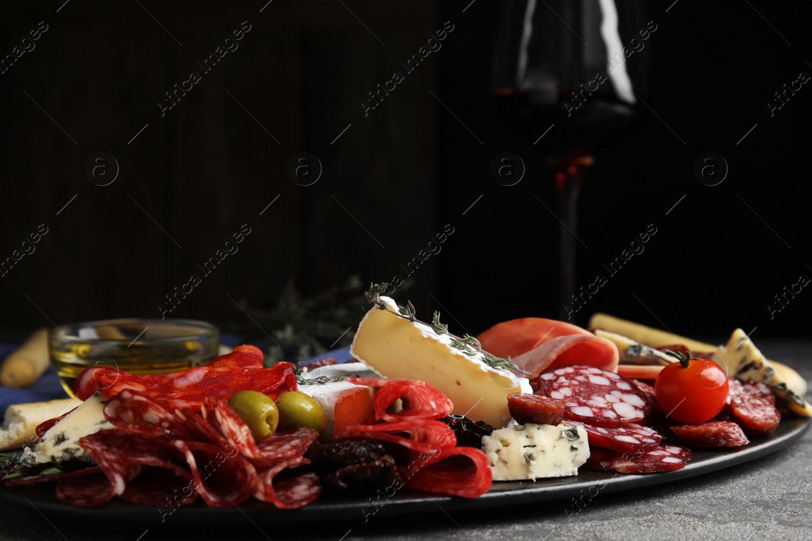 Photo of Tasty ham with other delicacies served on grey table