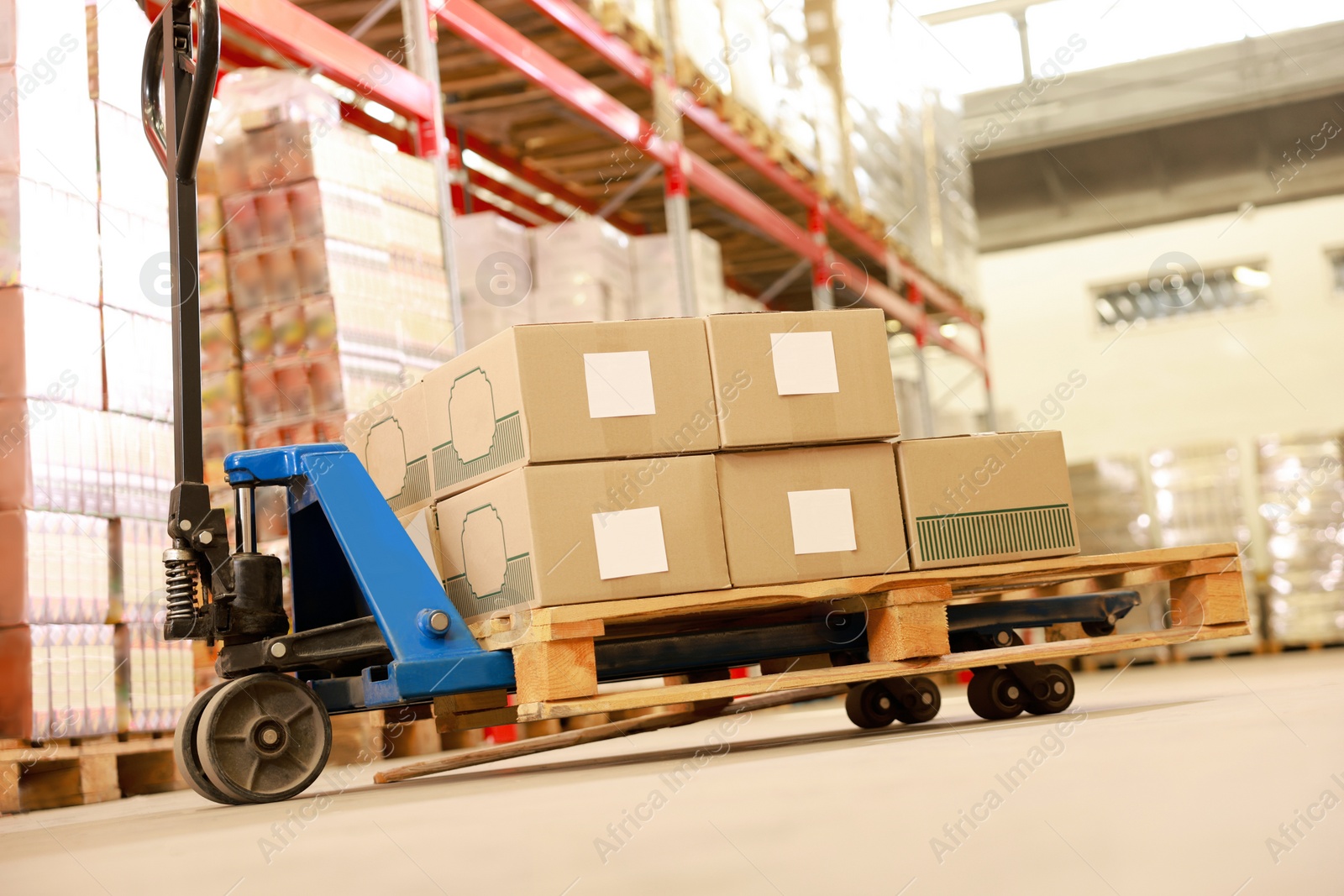 Image of Manual forklift with cardboard boxes in warehouse. Logistics concept