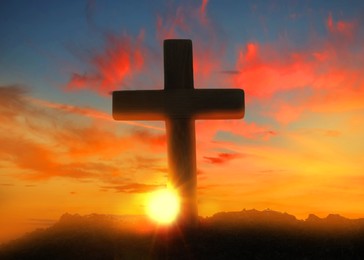 Image of Silhouette of Christian cross outdoors at sunset