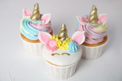 Three cute sweet unicorn cupcakes on white table