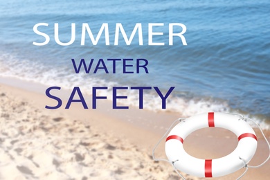Image of Summer water safety. Life buoy on sandy beach near sea 