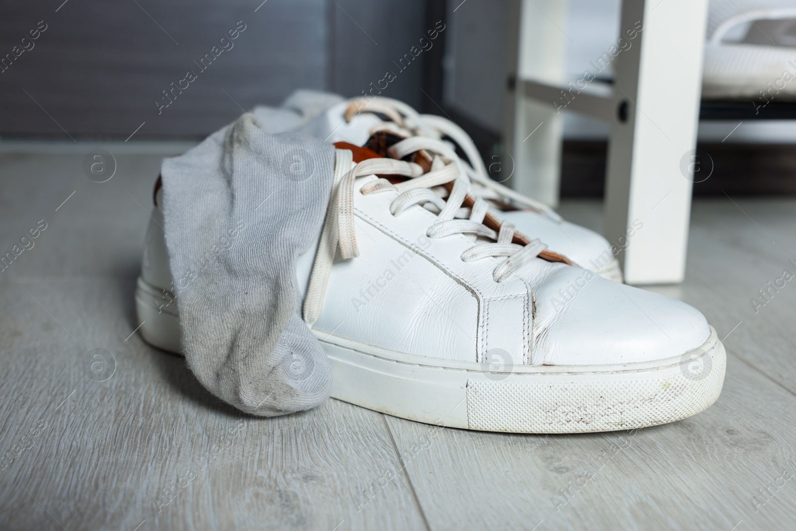 Photo of Sneakers with dirty socks on white wooden floor indoors