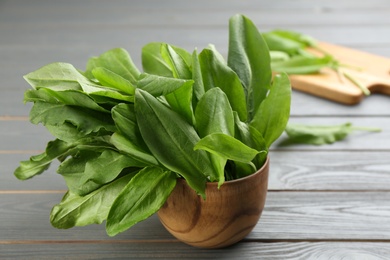 Photo of Fresh green sorrel leaves on grey wooden table, closeup