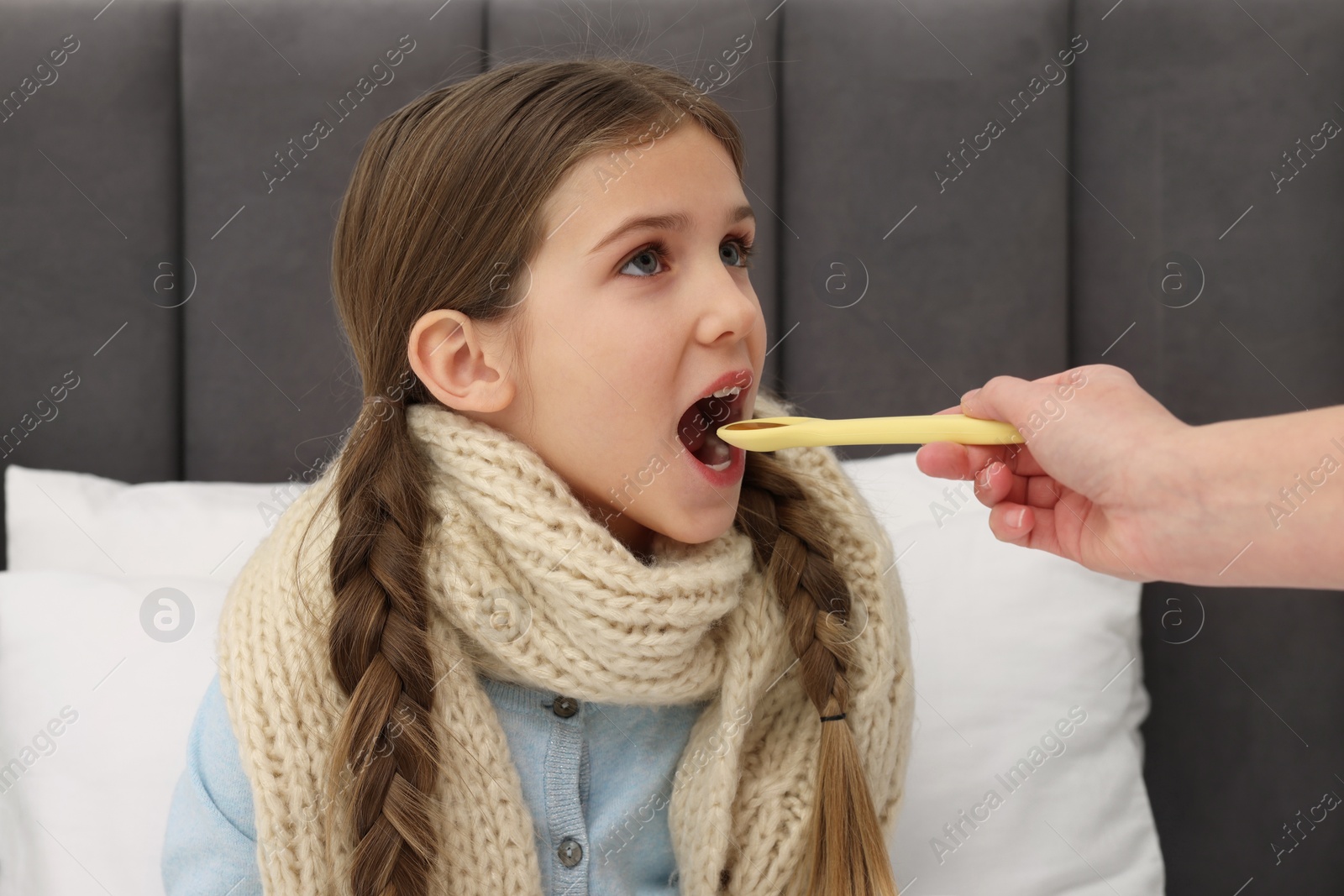 Photo of Mother giving cough syrup to her daughter at home