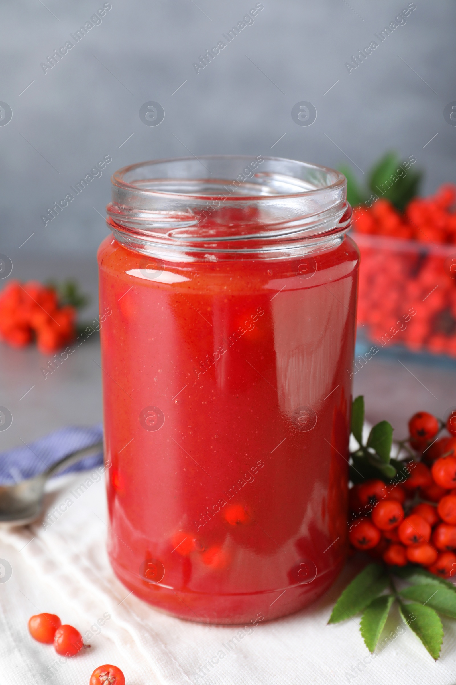 Photo of Delicious rowan jam in glass jar on grey table