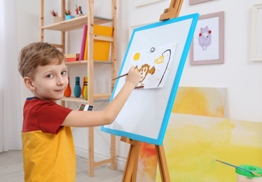 Cute little child painting during lesson in room