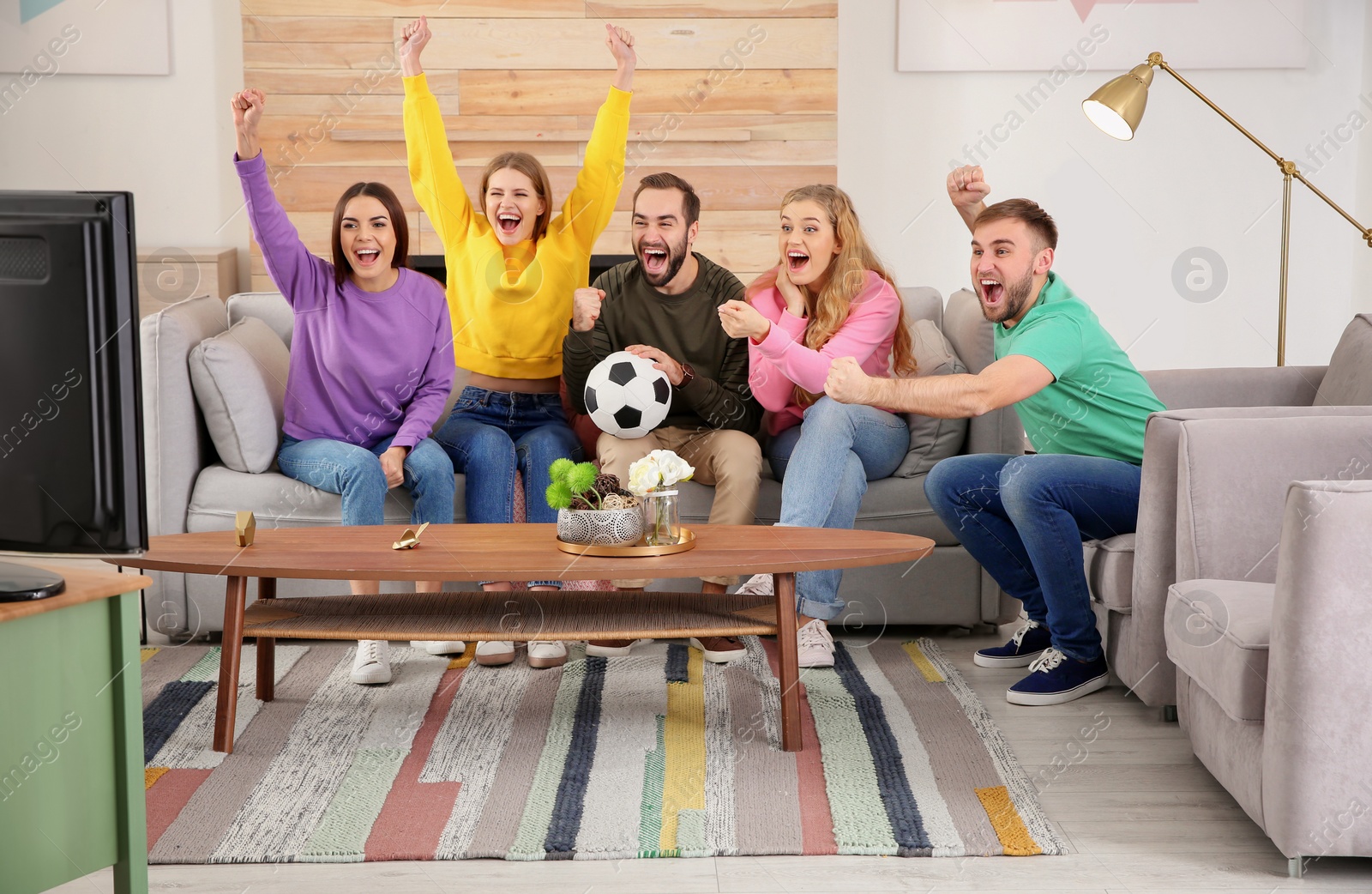 Photo of Group of friends celebrating victory of favorite soccer team in living room