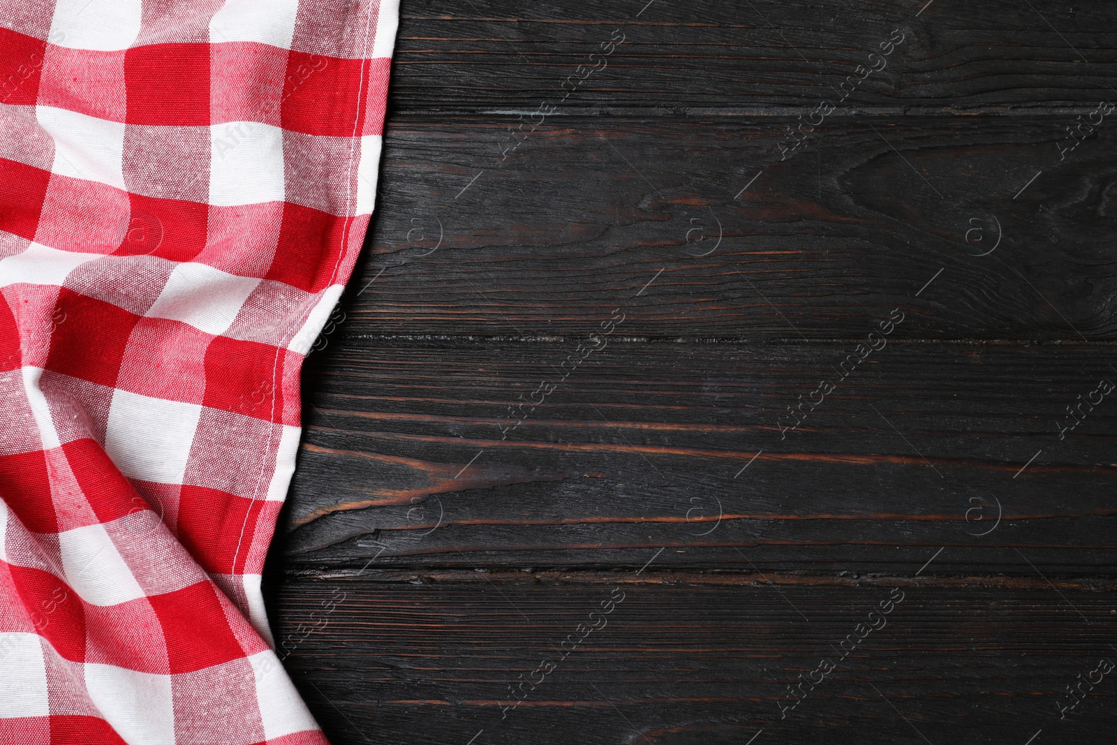 Photo of Checkered picnic blanket on color wooden background, top view. Space for text